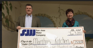 Timothy McLaughlin, SJWC’s Community Relations Manager, presents a check to Edita Cruz, Martha’s Kitchen Executive Director, to cover all meals served in January.